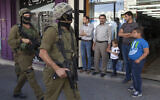 Illustrative: Israeli soldiers walk though a Hebron market on June 19, 2014. (AP/Majdi Mohammed)