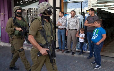 Illustrative: Israeli soldiers walk though a Hebron market on June 19, 2014. (AP/Majdi Mohammed)