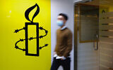 Illustrative: A man walks past the logo of the Amnesty International at its office in Hong Kong, October 25, 2021. (AP Photo/Vincent Yu)