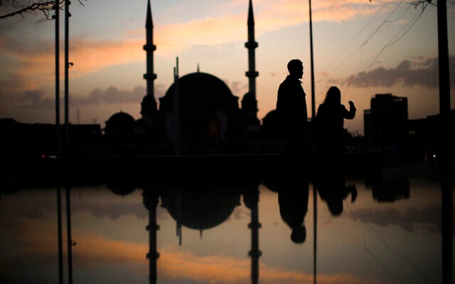 People walk next to Taksim mosque as the sun sets during the first day of the Muslim holy fasting month of Ramadan, in Istanbul, Turkey, April 2, 2022. (AP/Francisco Seco)