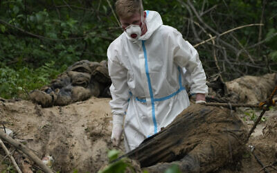 A member of an extraction crew works during an exhumation at a mass grave near Bucha, on the outskirts of Kyiv, Ukraine, June 13, 2022. (AP Photo/Natacha Pisarenko)
