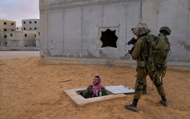 Israeli soldiers aim their weapons toward their colleague dressed as a Palestinian fighter, while he exits from a fake tunnel, during training session simulating urban fighting at the Tzeelim army base, southern Israel, Jan. 4, 2022. (Oded Balilty/AP)