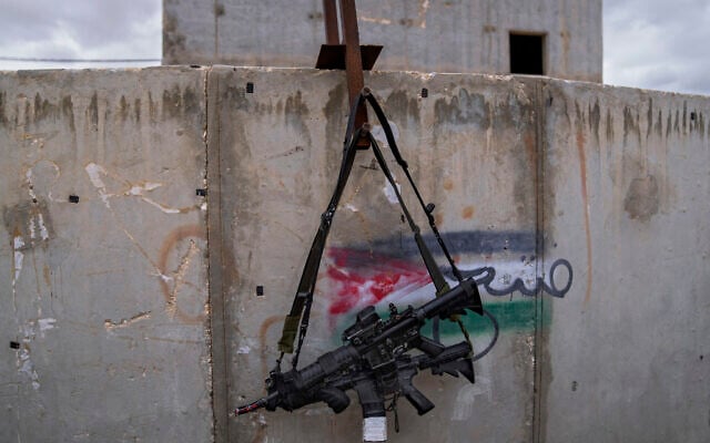 Two M-16 rifles hanging on a wall with a graffiti featuring the Palestinian flag at the IDF Urban Warfare Training Center at the Tzeelim army base, southern Israel,  Feb. 10, 2022. (Oded Balilty/AP)