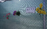 Artificial flowers on a fence on June 21, 2022, surrounding the site where the Champlain Towers South collapsed killing 98 people last year in Surfside, Florida. (AP/Wilfredo Lee)