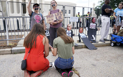 Anti-abortion activists Maggie Donica, 21, left, and Grace Rykaczewski, 21, kneel and pray in front of abortion-rights activists following the Supreme Court's decision to overturn Roe v. Wade, federally protected right to abortion, in Washington, Friday, June 24, 2022. (AP/Jacquelyn Martin)