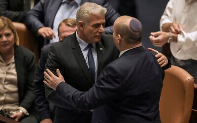 Outoing Prime Minister Naftali Bennett, right, and his interim successor Yair Lapid speak after the passage of a bill to dissolve the Knesset, June 30, 2022. (AP Photo/Ariel Schalit)