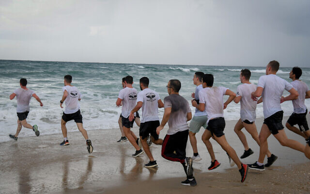 Israeli teens run as part of a pre-army preparatory program at Palmachim beach, November 15, 2020. (Flash90)
