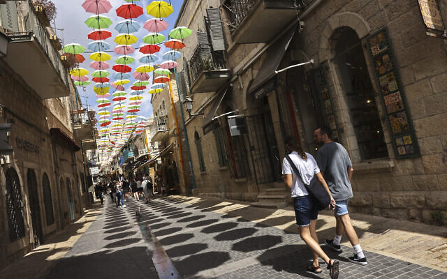 People walk in central Jerusalem where the municipality hung coloful umbrellas to create shade for passersby, on September 10, 2021. (Nati Shohat/Flash90) People walk in central Jerusalem where the municipality hung coloful umbrellas to create shade for passersby, on September 10, 2021. (Nati Shohat/Flash90)