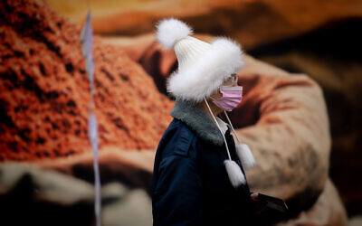 A woman wearing a face mask walks in downtown Jerusalem, March 16, 2022. (Yonatan Sindel/Flash90)