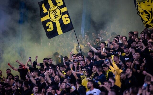Beitar Jerusalem fans cheer and wave a 'La Familia' flag during a match between Beitar Jerusalem and Hapoel Jerusalem at Teddy Stadium in Jerusalem on April 23, 2022. (Oren ben Hakoon/Flash90)