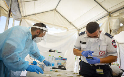 Magen David workers take COVID-19 rapid antigen tests from Israelis, at a Magen David Adom drive-thru complex in Jerusalem, on June 20, 2022. (Olivier Fitoussi/Flash90)