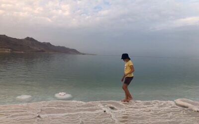 Illustrative image: An Israeli teen walks along a promenade into Israel's Dead Sea, 2021. (Amanda Borschel-Dan/ToI)