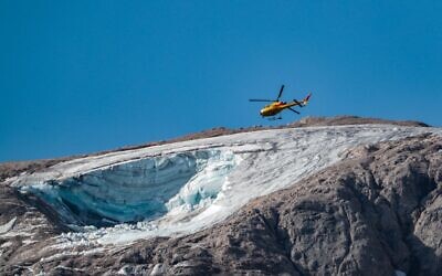 A rescue helicopter flies on July 4, 2022 over the glacier that collapsed the day before on the mountain of Marmolada, the highest in the Dolomites (Pierre TEYSSOT / AFP)