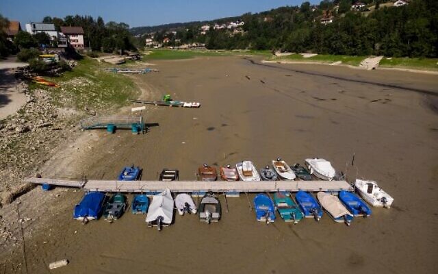Boats in Brenets Lake (Lac des Brenets), part of the Doubs River, which has dried up due to a combination of factors, including geological faults that drain the river, decreased rainfall and heat waves. It acts as a natural border between eastern France and western Switzerland, July 18, 2022. (Fabrice Coffrini/AFP)
