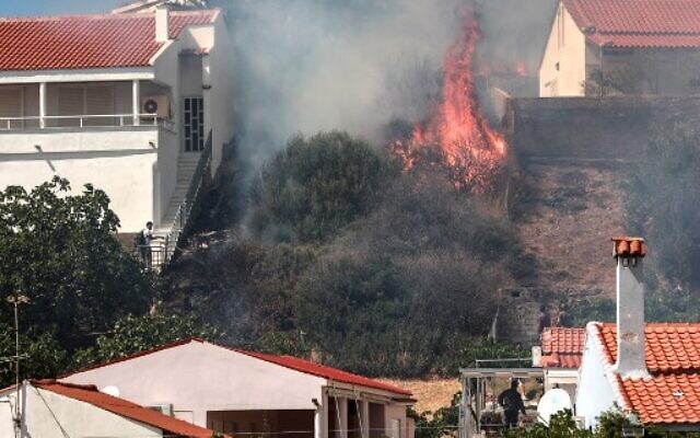 Residents look at fire burning trees near the houses at Vatera coastal resort on the eastern island of Lesbos on July 23, 2022. (Manolis LAGOUTARIS / AFP) Residents look at fire burning trees near the houses at Vatera coastal resort on the eastern island of Lesbos on July 23, 2022. (Manolis LAGOUTARIS / AFP)