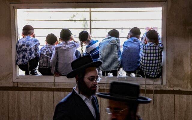 Illustrative: Ultra-Orthodox Jewish children watch through a window the funeral procession of prominent Rabbi Yitzchok Tuvia Weiss in Jerusalem, July 31, 2022. (Menahem KAHANA / AFP) Illustrative: Ultra-Orthodox Jewish children watch through a window the funeral procession of prominent Rabbi Yitzchok Tuvia Weiss in Jerusalem, July 31, 2022. (Menahem KAHANA / AFP)