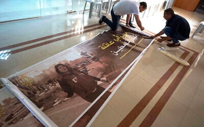 Palestinians prepare posters with pictures of Al Jazeera journalist Shireen Abu Akleh and Arabic that reads, "Shireen, the pulse of Palestine," at the office of Al Jazeera channel, in the West Bank city of Ramallah, Wednesday, May 11, 2022. (AP/Nasser Nasser)