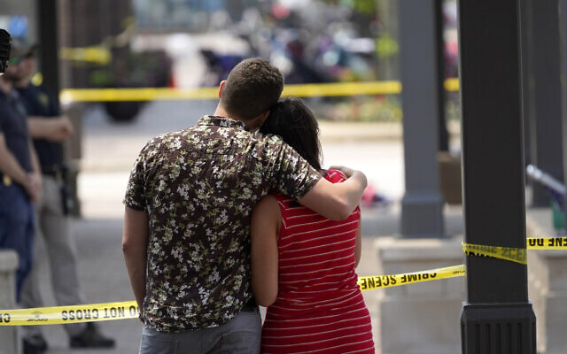Brooke and Matt Strauss, who were married Sunday, look toward the scene of the mass shooting in downtown Highland Park, Ill., a Chicago suburb, after leaving their wedding bouquets near the scene of Monday's mass shooting, Tuesday, July 5, 2022. (AP Photo/Charles Rex Arbogast)