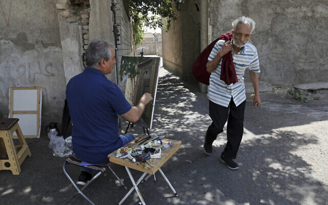 Painter Hassan Naderali paints an old building in the historic neighborhood of Oudlajan, in Tehran, Iran, June 20, 2022. (Vahid Salemi/AP) Painter Hassan Naderali paints an old building in the historic neighborhood of Oudlajan, in Tehran, Iran, June 20, 2022. (Vahid Salemi/AP)