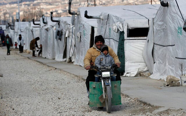 FILE - A displaced Syrian man and his son ride a motorcycle, as they drive between the tents at a refugee camp, in Bar Elias, in eastern Lebanon's Bekaa Valley, March 5, 2021. (AP/Hussein Malla, File) FILE - A displaced Syrian man and his son ride a motorcycle, as they drive between the tents at a refugee camp, in Bar Elias, in eastern Lebanon's Bekaa Valley, March 5, 2021. (AP/Hussein Malla, File)