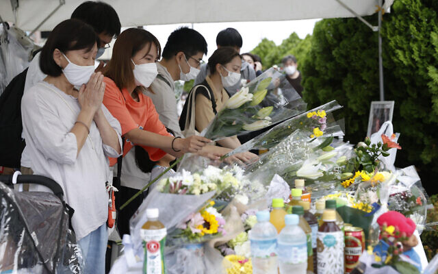 People offer prayers near the site of the fatal shooting of former Japanese Prime Minister Shinzo Abe, in Nara, western Japan July 9, 2022. (Kyodo News via AP) People offer prayers near the site of the fatal shooting of former Japanese Prime Minister Shinzo Abe, in Nara, western Japan July 9, 2022. (Kyodo News via AP)