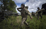 A Ukrainian serviceman carries a 155 mm artillery shell before firing at Russian positions from a US-supplied M777 howitzer in Kharkiv region, Ukraine, July 14, 2022. (AP Photo/Evgeniy Maloletka)