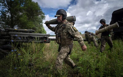 A Ukrainian serviceman carries a 155 mm artillery shell before firing at Russian positions from a US-supplied M777 howitzer in Kharkiv region, Ukraine, July 14, 2022. (AP Photo/Evgeniy Maloletka)