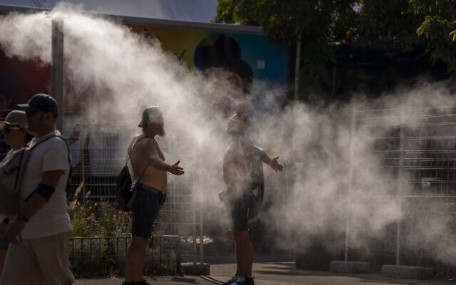Two men cool themselves with water from a public sprinkler on a hot and sunny day in Barcelona, Spain, July 16, 2022. (AP Photo/Emilio Morenatti) Two men cool themselves with water from a public sprinkler on a hot and sunny day in Barcelona, Spain, July 16, 2022. (AP Photo/Emilio Morenatti)