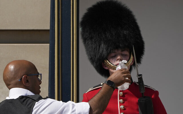 A police officer givers water to a British soldier wearing a traditional bearskin hat, on guard duty outside Buckingham Palace, during hot weather in London, Monday, July 18, 2022. (AP Photo/Matt Dunham) A police officer givers water to a British soldier wearing a traditional bearskin hat, on guard duty outside Buckingham Palace, during hot weather in London, Monday, July 18, 2022. (AP Photo/Matt Dunham)