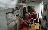 A paramedic assists an injured man in an ambulance after a Russian attack at Barabashovo market in Kharkiv, Ukraine, Thursday, July 21, 2022. (AP Photo/Evgeniy Maloletka)