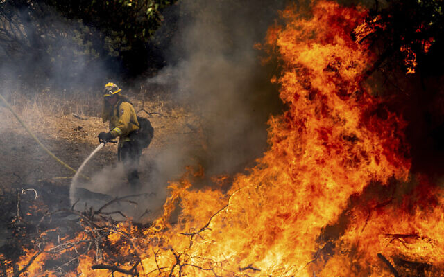 A firefighter sprays water while battling the Oak Fire in Mariposa County, Caliornia, July 23, 2022. (AP Photo/Noah Berger)