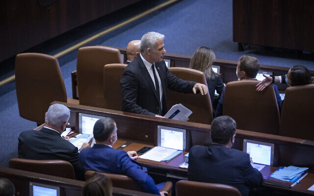 Then-Foreign Minister Yair Lapid walks by opposition leader Benjamin Netanyahu in the Knesset on November 8, 2021. (Olivier Fitoussi/Flash90) Then-Foreign Minister Yair Lapid walks by opposition leader Benjamin Netanyahu in the Knesset on November 8, 2021. (Olivier Fitoussi/Flash90)