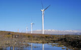 Renewable energy wind turbines as seen next to the snowy peaks of Mount Hermon on January 3, 2021, in the northern Golan Heights. (Michael Giladi/Flash90)