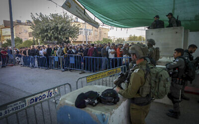 Israeli soldiers stand guard, as Palestinians make their way through a checkpoint to attend Friday prayers at Jerusalem's Al-Aqsa mosque, near the West Bank city of Bethlehem, April 29, 2022. (Wisam Hashlamoun/ Flash90/ File)