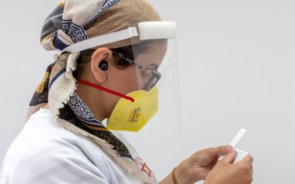 A health care worker processes swab samples from Israelis at a testing center, on June 28, 2022. (Yossi Aloni/Flash90) A health care worker processes swab samples from Israelis at a testing center, on June 28, 2022. (Yossi Aloni/Flash90)