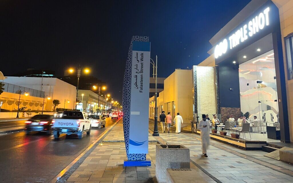 A sign for the Palestine Street walkway with King Fahd's Fountain in the backdrop  in Jeddah, Saudi Arabia on July 16, 2022. (Jacob Magid/Times of Israel)