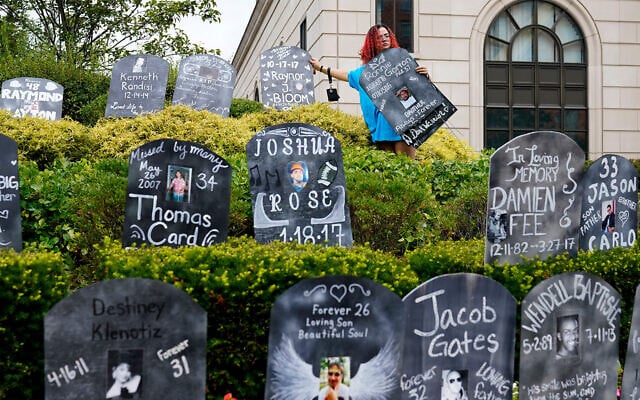 An activist sets up cardboard gravestones with the names of victims of opioid overdose outside the courthouse where the Purdue Pharma bankruptcy case was taking place in White Plains, New York, on August 9, 2021. (AP Photo/Seth Wenig) An activist sets up cardboard gravestones with the names of victims of opioid overdose outside the courthouse where the Purdue Pharma bankruptcy case was taking place in White Plains, New York, on August 9, 2021. (AP Photo/Seth Wenig)