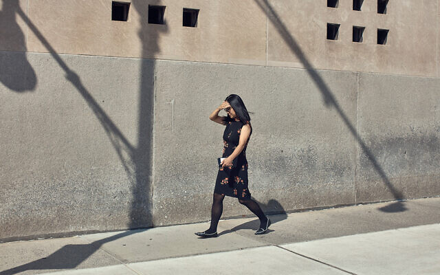 A woman walks under the sun during a summer heat wave in New York, July 21, 2022. (AP Photo/Andres Kudacki)