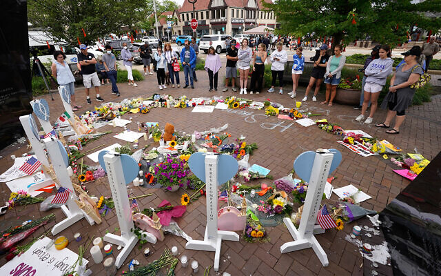 Area residents visit a memorial to the seven people who lost their lives in the Highland Park, Ill., Fourth of July mass shooting, July 6, 2022, in Highland Park. (AP Photo/Charles Rex Arbogast)