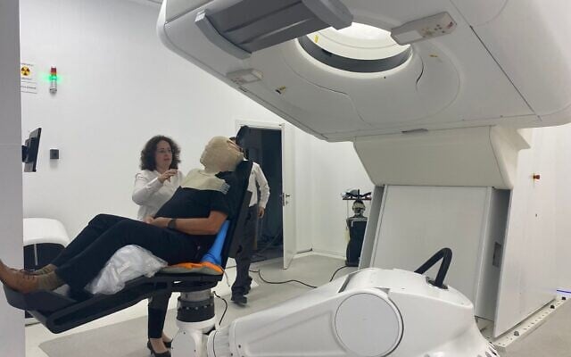 The new facility for proton therapy at Hadassah Medical Center in Jerusalem; a patient in a chair wears a plastic mask that covers the face to protect it from radiation (Courtesy of Hadassah Medical Center) The new facility for proton therapy at Hadassah Medical Center in Jerusalem; a patient in a chair wears a plastic mask that covers the face to protect it from radiation (Courtesy of Hadassah Medical Center)