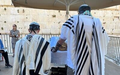 Seth Mann, left, reads from a Torah scroll during his bar mitzvah ceremony at the Western Wall's egalitarian section on June 30, 2022. (Courtesy/Mann family)