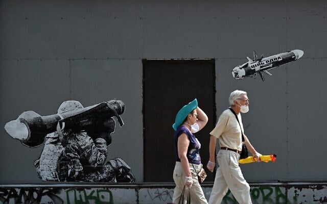 A couple walks past a graffiti on a wall depicting a Ukrainian serviceman making a shot with a US-made Javelin portable anti-tank missile system, in Kyiv, on July 29, 2022. (Sergei SUPINSKY / AFP) A couple walks past a graffiti on a wall depicting a Ukrainian serviceman making a shot with a US-made Javelin portable anti-tank missile system, in Kyiv, on July 29, 2022. (Sergei SUPINSKY / AFP)