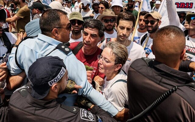 Simha and Leah Goldin (center L and R), the parents of late Israeli soldier Hadar Goldin whose body has been held by Hamas since the 2014 Gaza conflict, are prevented from proceeding by Israeli police forces in the southern kibbutz of Karmia on August 5, 2022. (JACK GUEZ / AFP)