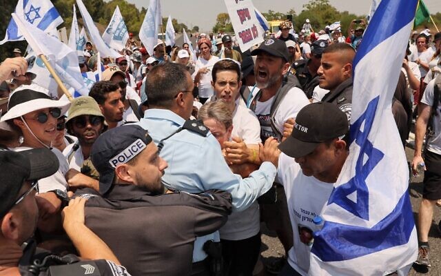 Leah Goldin (C), mother of late Israeli soldier Hadar Goldin whose body has been held by Hamas since the 2014 Gaza conflict, is prevented along with others from proceeding by Israeli police forces in the southern Israeli kibbutz of Karmia on August 5, 2022 during a march to demand the return of Goldin's remains and the return of other Israelis held in Gaza back to Israel. (JACK GUEZ / AFP)
