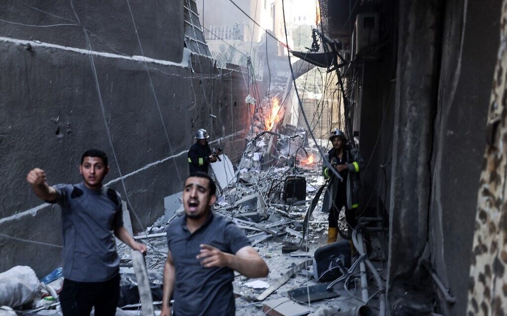 Rescuers and firefighters put out a fire amid the destruction following an Israeli air strike on Gaza City, on August 5, 2022 (Mohammed ABED / AFP)