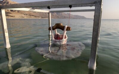 A once-red ballerina dress, is submerged by multidisciplinary Israeli artist Sigalit Landau in the salty Dead Sea water, at the Ein Bokek resort, on August 2, 2022. (MENAHEM KAHANA / AFP)