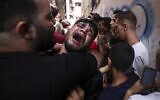 A friend of a young Palestinian killed during the night in disputed circumstances in the Jabaliya refugee camp in the northern Gaza Strip reacts during his funeral in the same camp, on August 7, 2022 (MAHMUD HAMS / AFP)