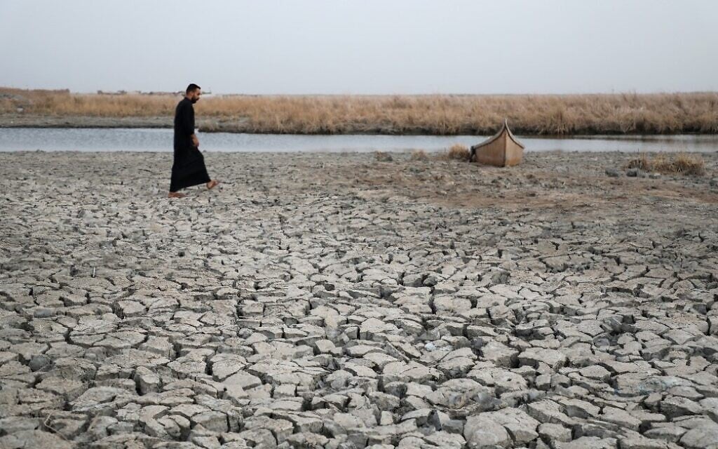 A demonstrator approaches a boat stuck in the dried-up bank of a canal, during a rally at the Umm El Wadaa marsh, south-east of the Iraqi city of Nasiriyah in the southern Dhi Qar province, on August 16, 2022, to demand solutions for water scarcity and drought. (Asaad NIAZI / AFP)