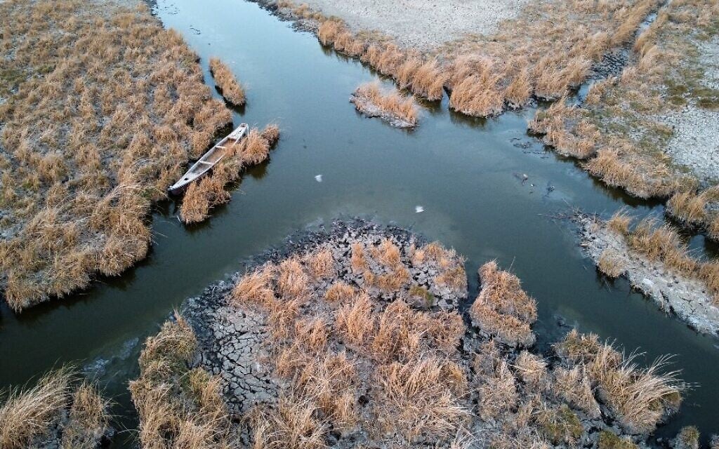 An aerial picture shows a view of a boat moored in a canal of the receding the Umm El Wadaa marsh, south-east of the Iraqi city of Nasiriyah in Iraq's southern Dhi Qar province, on August 16, 2022. (Asaad NIAZI / AFP)