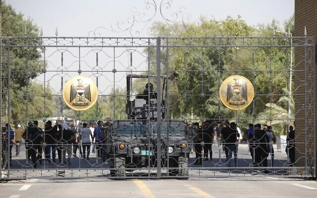 Iraqi police are pictured standing guard at the closed gate of the government headquarters in the capital Baghdad's Green Zone, on August 29, 2022. (Ahmad Al-Rubaye/AFP)